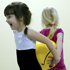 Two girls smile as they take part in Alta gymnastics' physical education program Tumblebugs for 3 to 5 year olds.