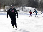 Premier Darrell Dexter skates with some kids on a homemade outdoor rink in Membertou.