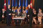 Premier Stephen McNeil smiles after sign his oath with Lt.-Gov. J.J. Grant and provincial deputy minister David Darrow.