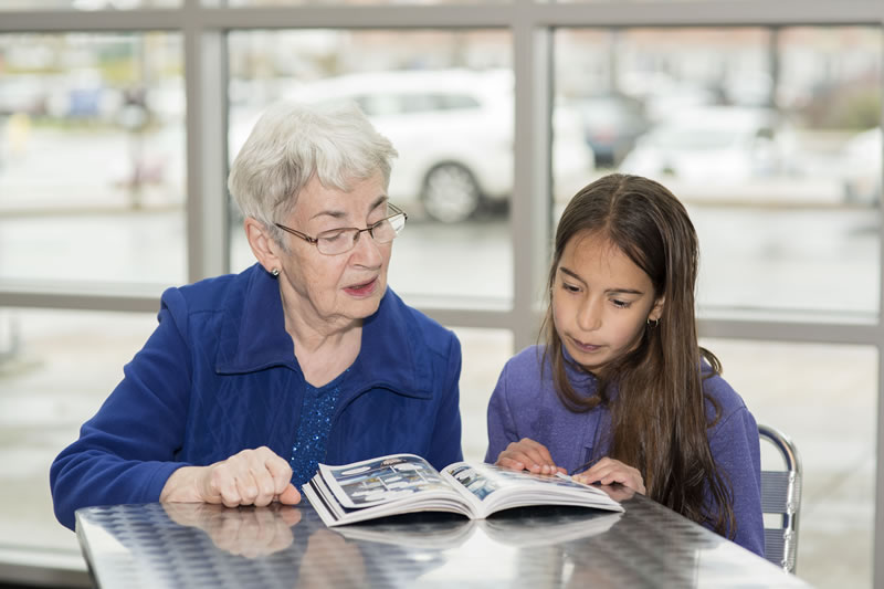 Senior citizen reading with a young girl