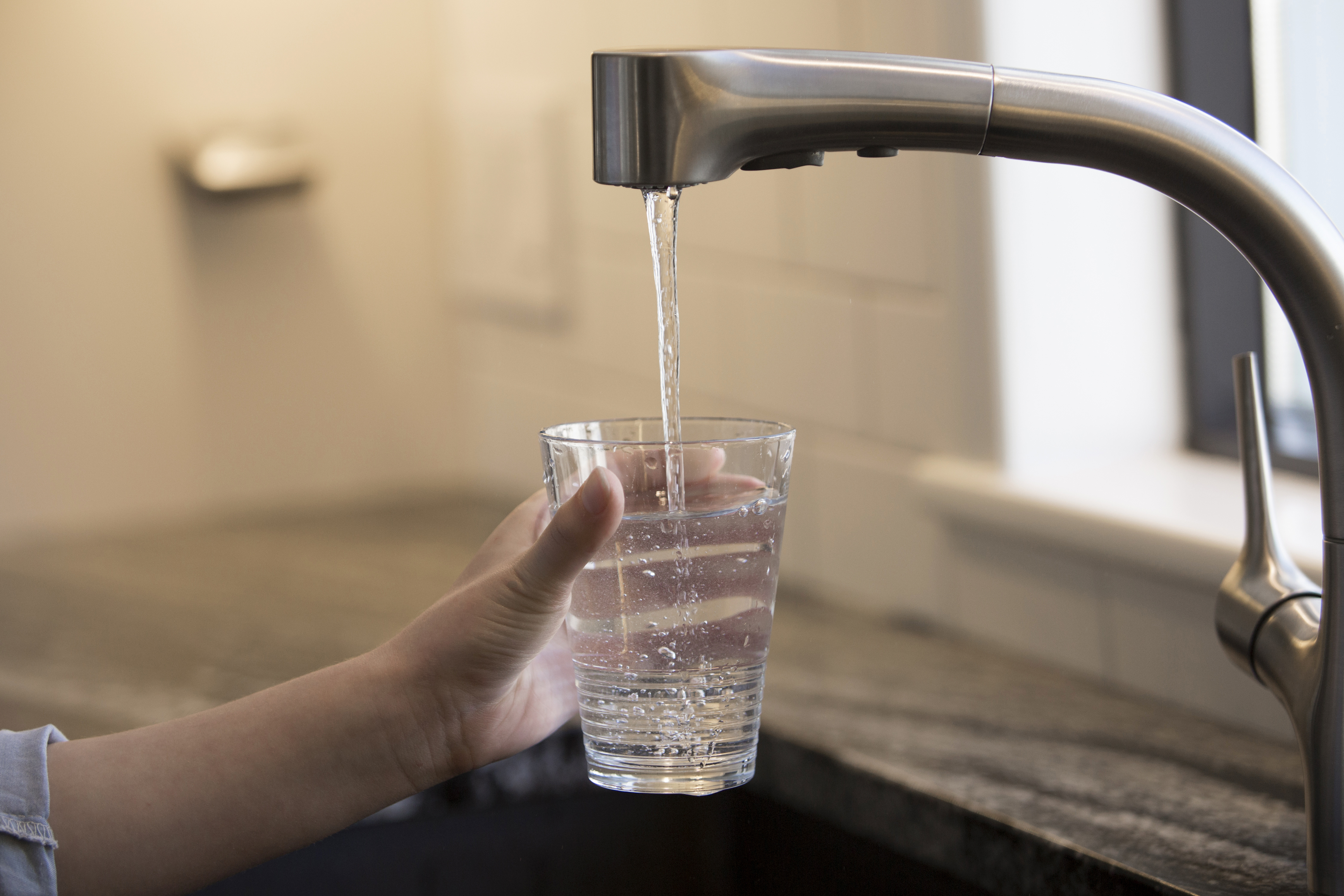 a person filling a glass of water