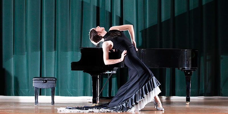 Dancer on stage with a piano in the background
