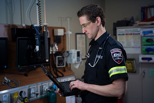 Paramedic working on a laptop in a hospital emergency room