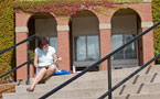 A student reads on the front steps of a university building