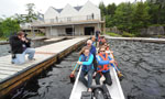 A crew of people at the announcement push away from the wharf in a dragon  boat at Maskwa Aquatic Club.