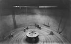 Crewmen carefully storing cable in large cable tank.