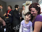 Ilira Mertezi smiles at daughter Era as Community Services Minister Denise Peterson-Rafuse, Education Minister Ramona Jennex and Health and Wellness Minister Maureen MacDonald answer questions in the background.