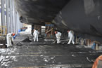 Shelburne Shipyard employees work underneath a vessel.