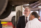 Transportation and Infrastructure Renewal Minister Maurice Smith looks on as a service technician explains tire tread wear.