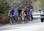 A group of cyclists bike along the shoulder of the highway.