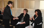 Pamela Harrison, Transition House Association of Nova Scotia, shakes hands with Status of Women Minister Marilyn More, as Chief Deborah Robinson, Acadia First Nations, applauds.