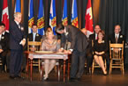 Premier Stephen McNeil signs after Labour and Advanced Education and Status of Women Minister Kelly Regan takes her oath.