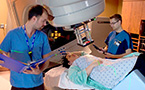 Two radiation therapists prepare a the linear accelerator for radiation therapy.